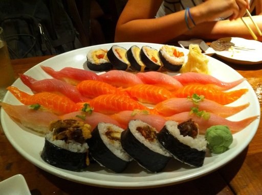 Salmon nigiri and rolls on a boat-shaped plate: one training image for the sushi class.